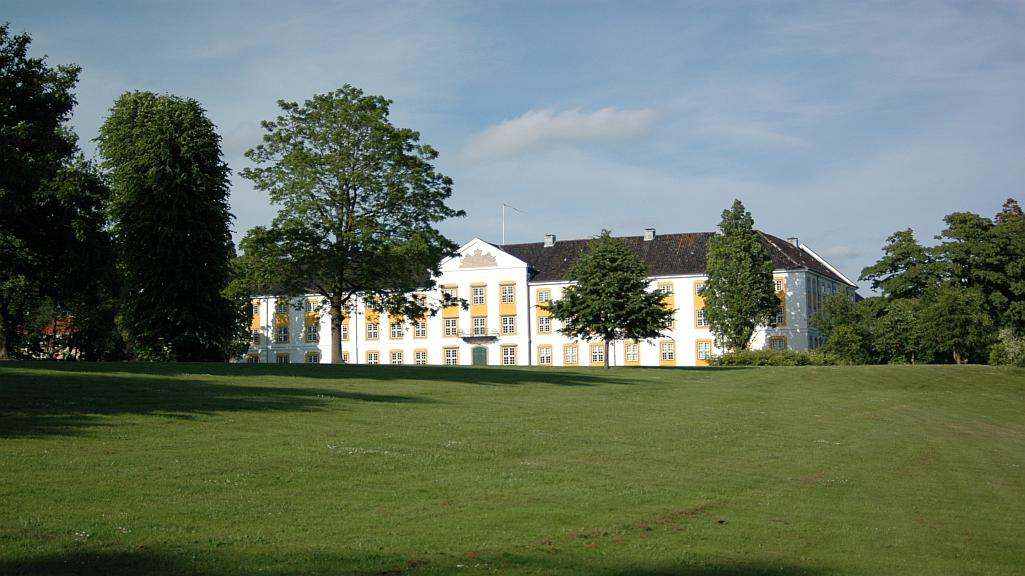 Augustenborg Slot — stort hvidt barokpalæ med gule vinduesrammer og mørkt tag, set fra den store grønne park